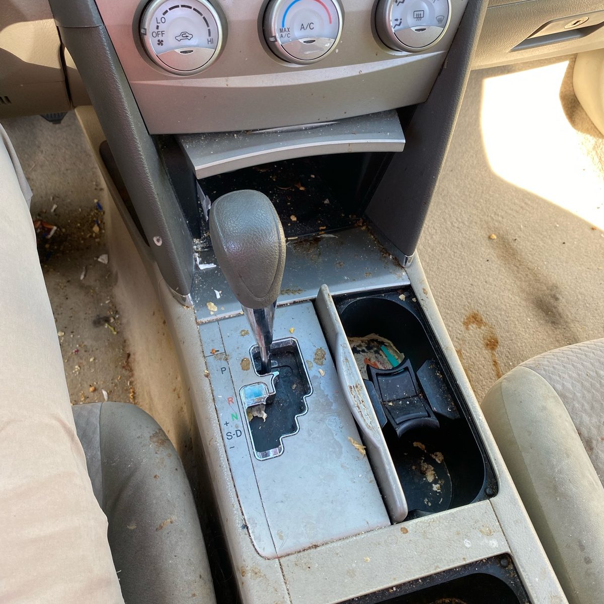Toyota Camry centre console covered in crumbs and spilled debris before an interior detail in Naples, Florida